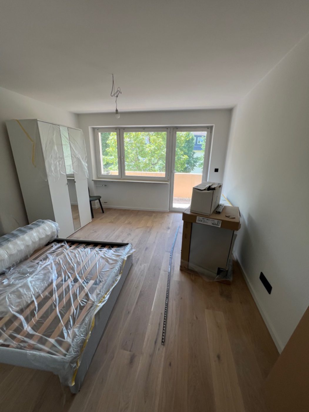Zimmer in der Endmontage mit Echtholzboden und noch verpackten Möbeln